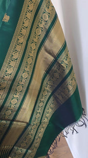 Dark green Silk Cotton saree with intricate gold pallu on a white background